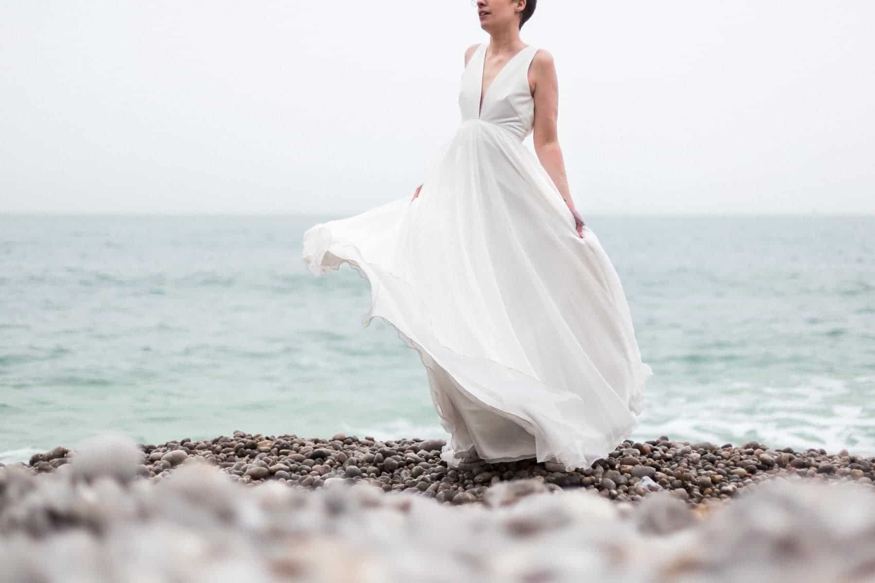 La mariée danse sur la plage d'Etretat en Normandie avec sa robe de créatrice